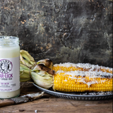 A plate of corn cobs beside a jar of Grumpy Gary's Gar-Lick Dip on a wooden surface