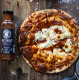Pizza with Grumpy Gary's Garlic hot sauce on a wooden surface