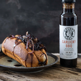 Garlicky BBQ sandwich on a plate with a bottle of Grumpy Gary's Garlicky BBQ sauce.