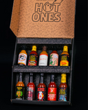 Collection of Hot Ones Season 29 hot sauce bottles in a Hot Ones branded decorative box on a black background