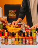 People dipping food into a bowl with 10 Season 29 Hot Ones hot sauce bottles in front of a 'Hot Ones' branded box.