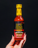 Bottle of Hot Ones Pickled Garlic Sriracha hot sauce held by a hand against a black background - buy online Australia | Blonde Chilli