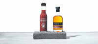 A bottle of Melbourne Hot Sauce - STARWARD Whisky Barrel Aged Hot Sauce. stands beside a bottle of STARWARD whisky.