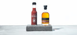 A bottle of Melbourne Hot Sauce - STARWARD Whisky Barrel Aged Hot Sauce. stands beside a bottle of STARWARD whisky.