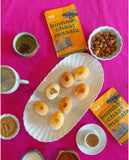 Aunty Jenny Bombay Chaat Masala spice blend on a dining table alongside Indian desserts.