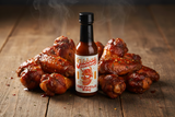 A bottle of Jibba's Chipotle BBQ sauce surrounded by chicken wings.