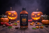Uncle Mungo's Pumpkin Ghost Hot Sauce with a background of jack-o-lanterns, pumpkin, ghost chillies, cinnamon, star anise and nutmeg.