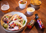 Culley's No 9 Ghost Chilli Hot Sauce and Culley's No 7 Tropical Caribbean Hot Sauce lying beside a plat of soft shell tacos.