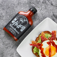 A bottle of Hoff & Pepper HOFF'S HAUS SAUCE lying beside a piece of toast with avociado and bacon and egg drizzled in Hoff's Haus Sauce