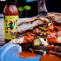 A plate of meats smothered in Culley's MILD Buffalo Wing Sauce. The sauce bottle is in the background.
