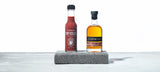 A bottle of Melbourne Hot Sauce - STARWARD Whisky Barrel Aged Hot Sauce. stands beside a bottle of STARWARD whisky.