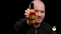Sean Evans holds a bottle of The Last Dab Apollo on the Hot Ones show.